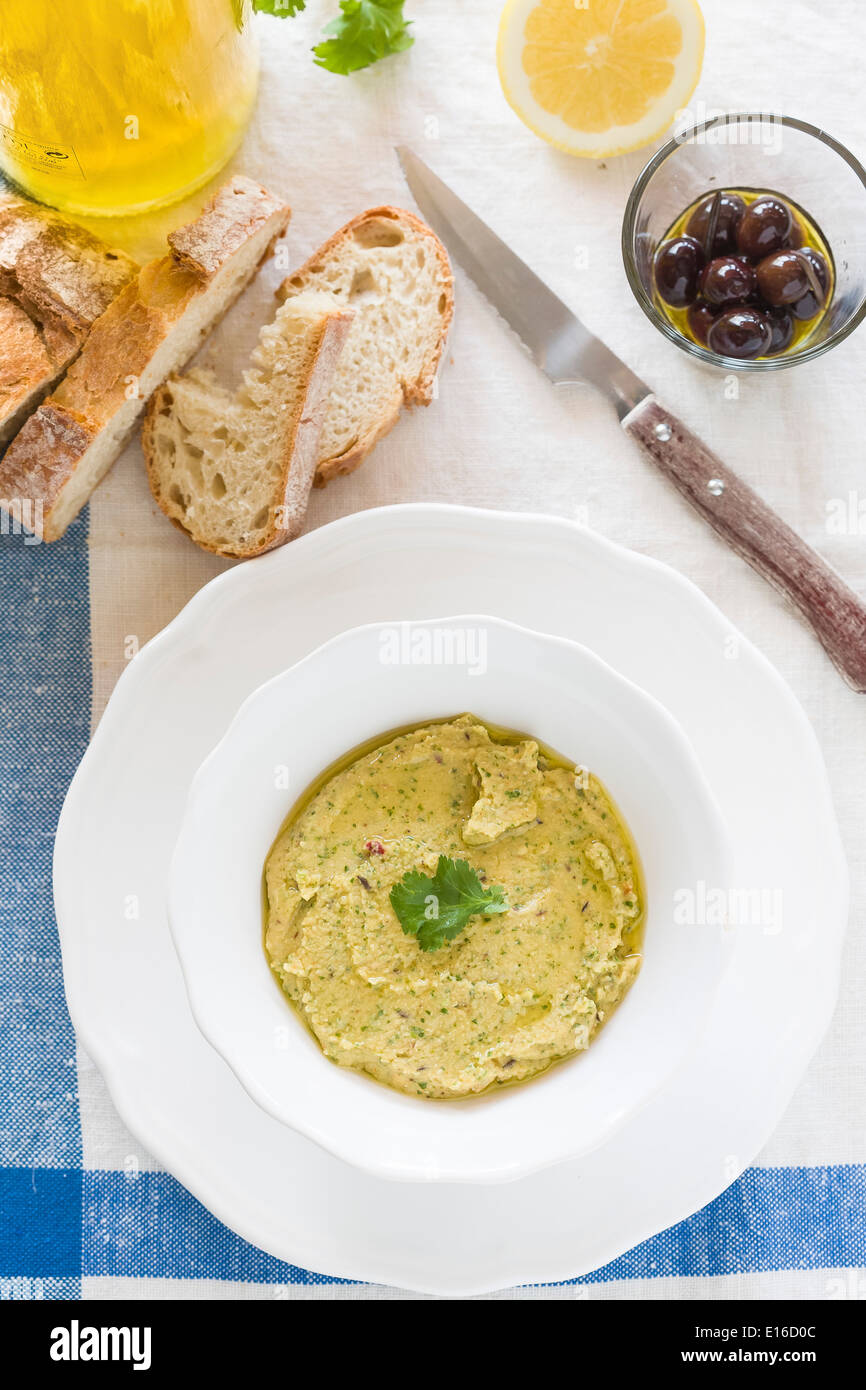 Coriander and lemon hummus, with rustic bread, olives, olive oil and lemon served on blue and white linen tablecloth Stock Photo