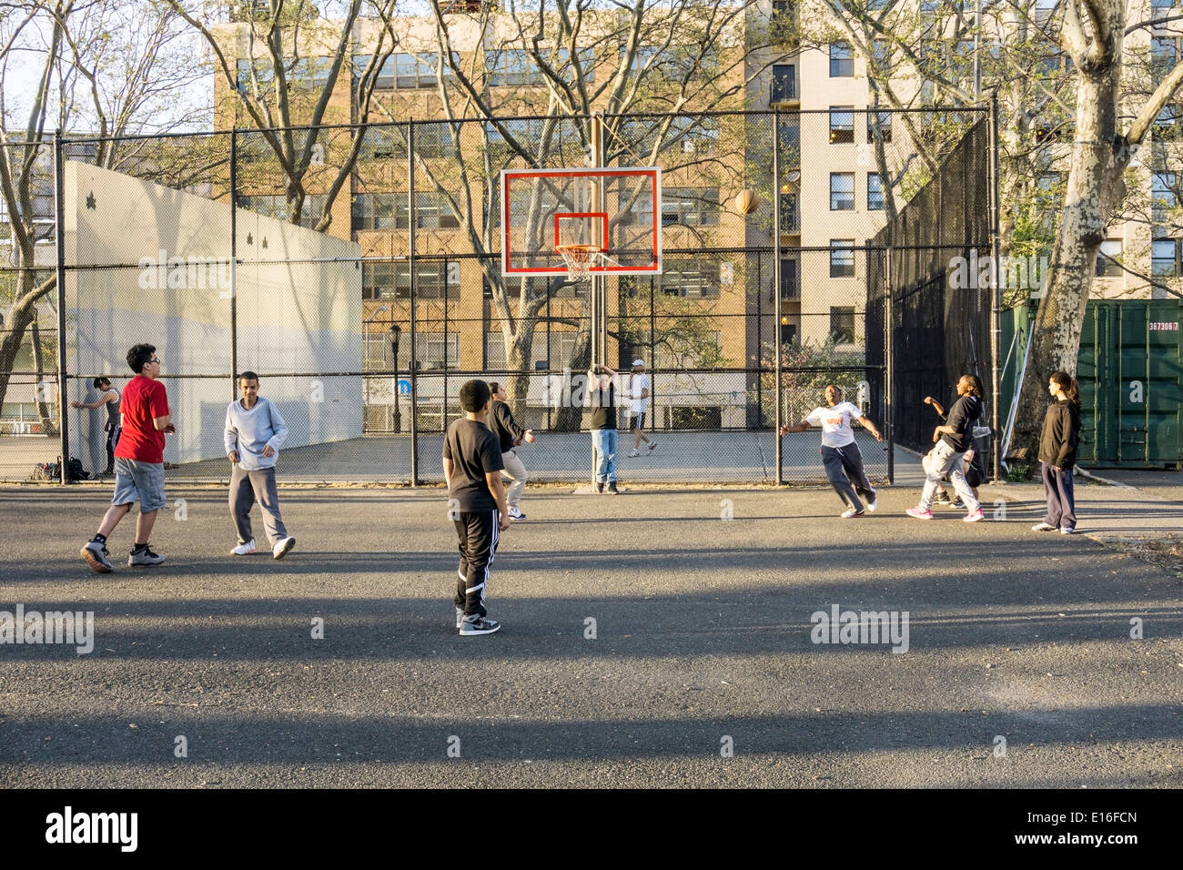 teen black girl aims for the basket in a good natured unisex street basketball game in DeWitt Clinton park Hells Kitchen Stock Photo