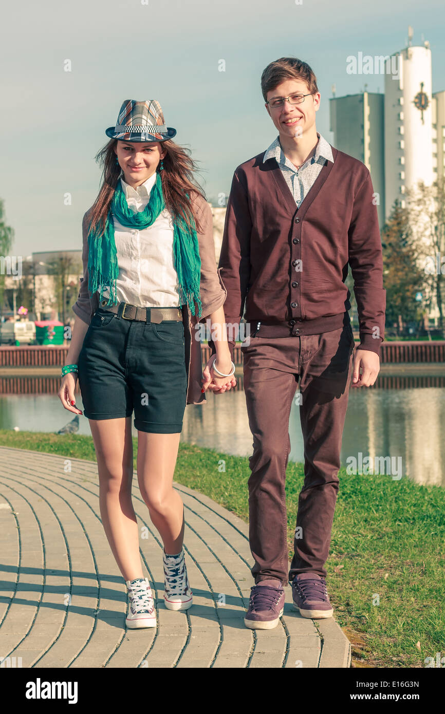 Young fashion elegant stylish couple posing in a European city park. Hipster cute girl with handsome man having fun outdoor. Stock Photo