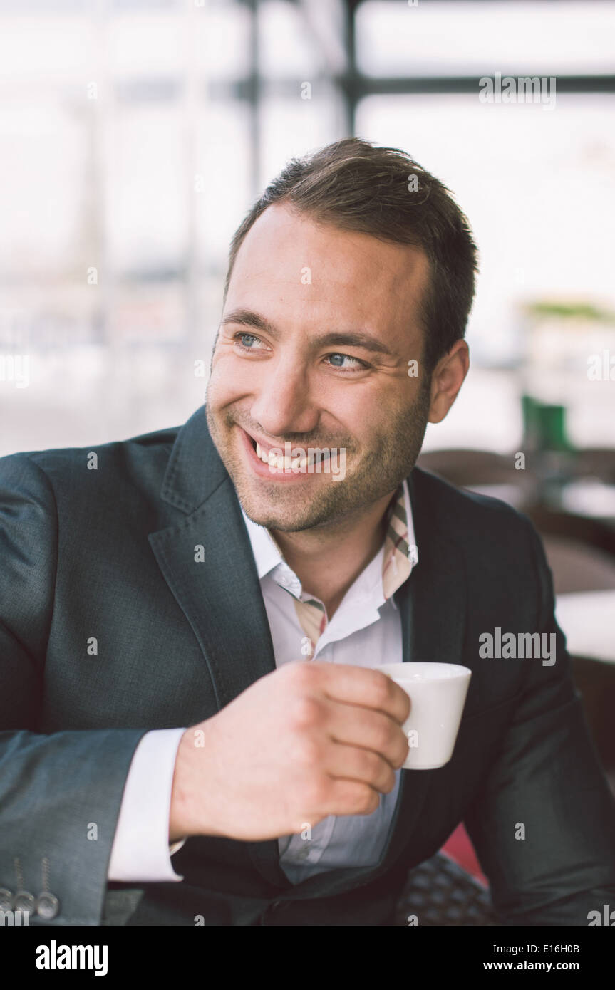 Handsome smiling man drinking espresso in cafe Stock Photo