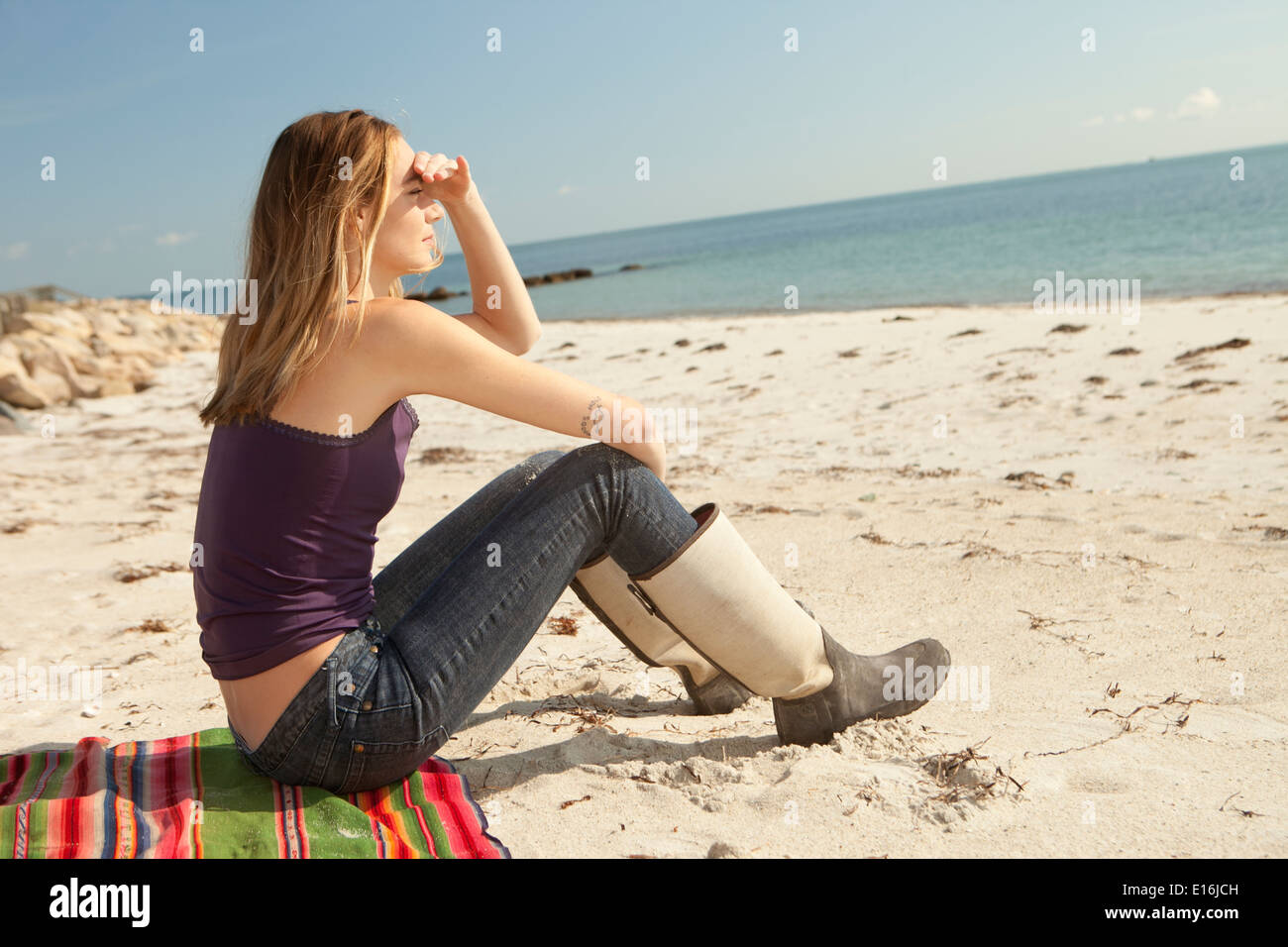 Young woman sitting on beach and looking at sea Stock Photo - Alamy