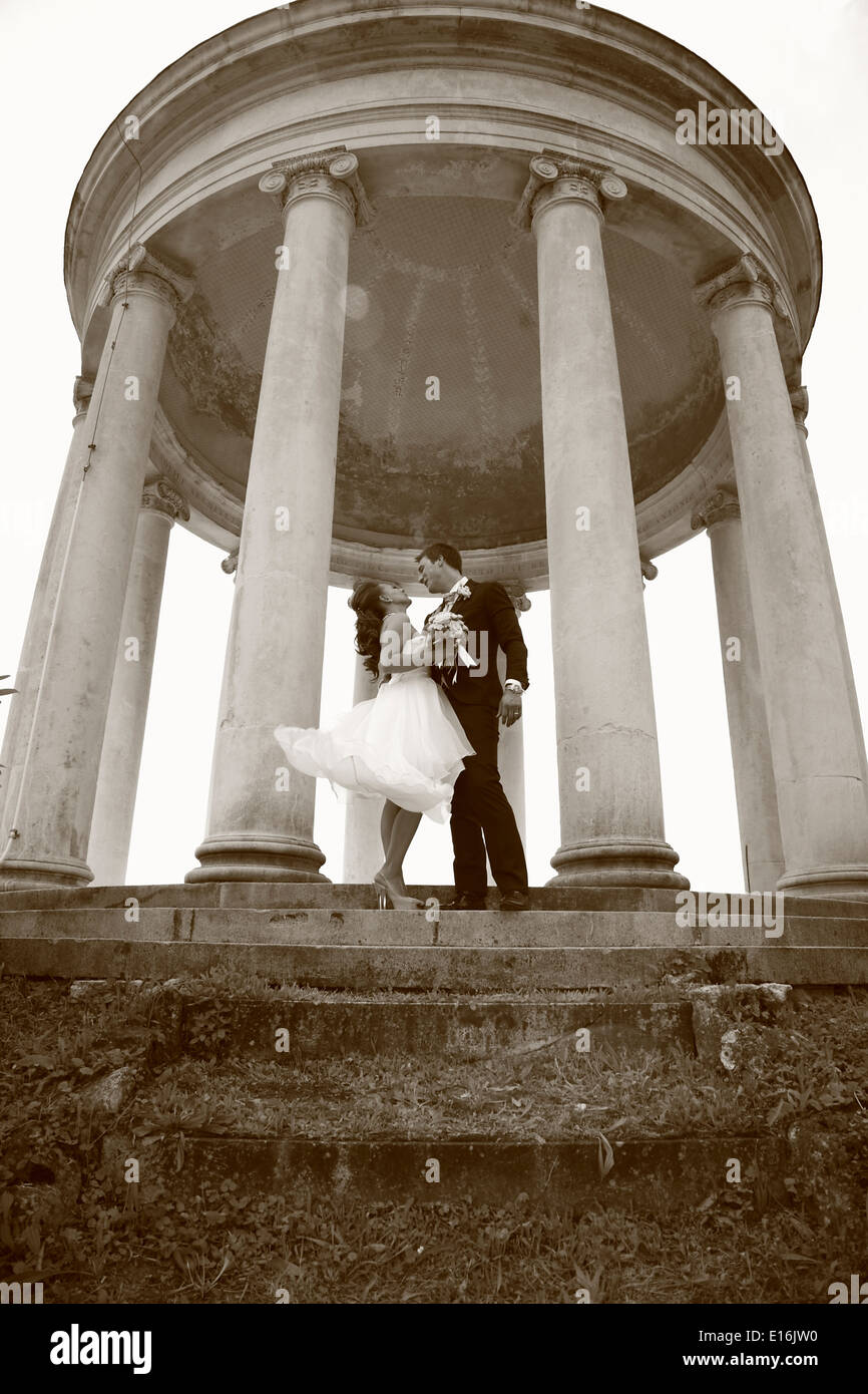 Newly wed couple standing behind columns Stock Photo