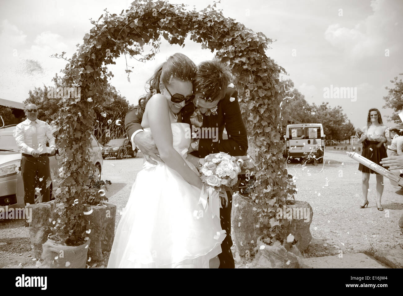 Newly wed couple walking under flower arch Stock Photo