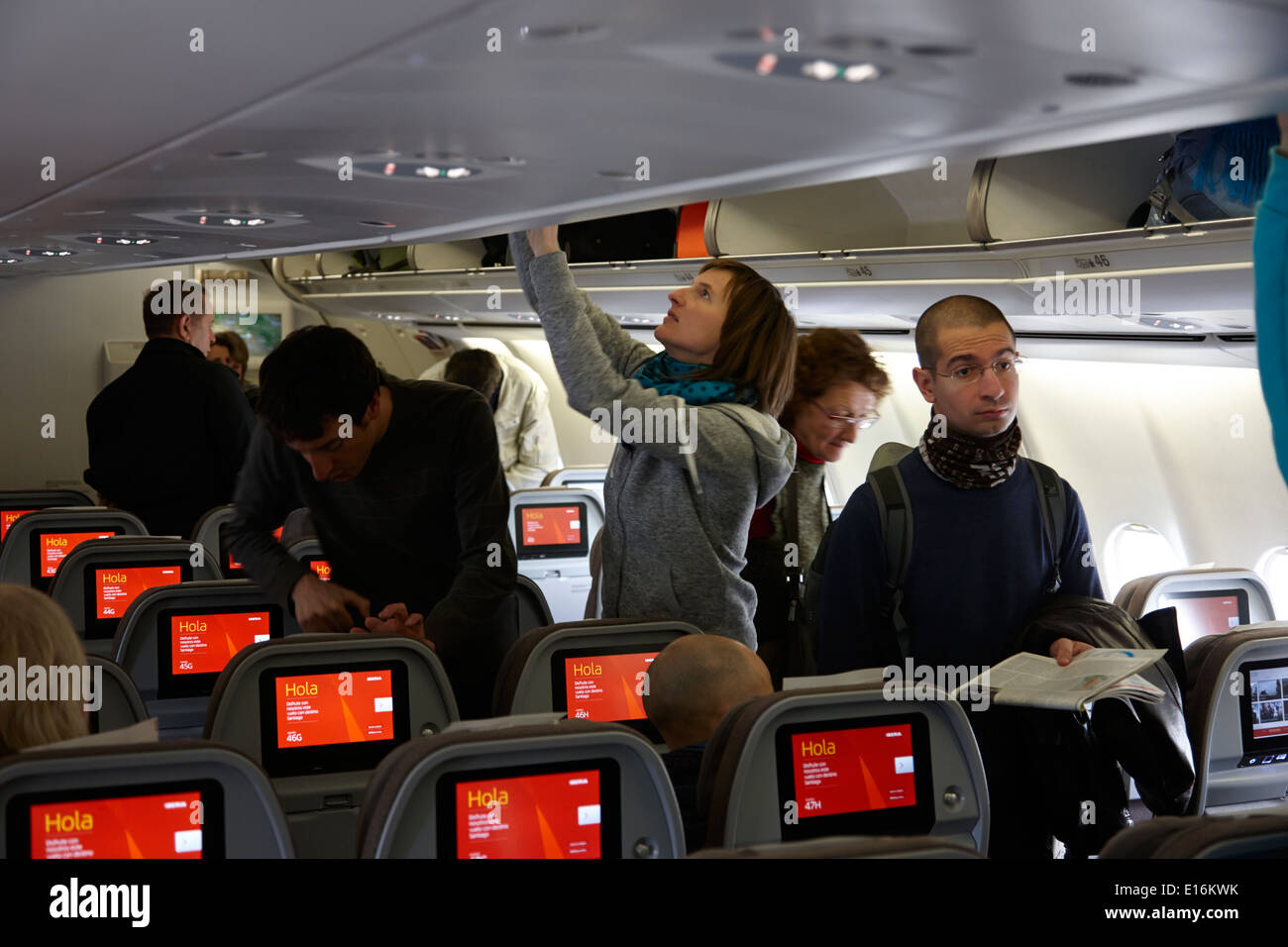 passengers loading overhead lockers and headrest screen entertainment on board iberia airbus aircraft spain Stock Photo