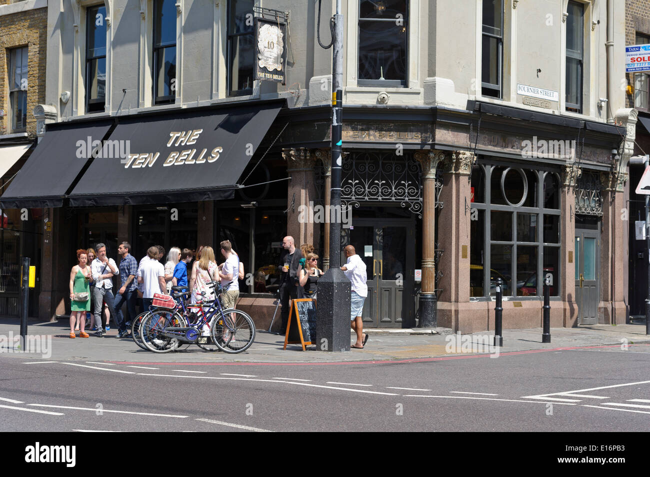 People drinking outside the Ten Bells Public House (Pub), one of the oldest Pubs in London, England, United Kingdom. Stock Photo