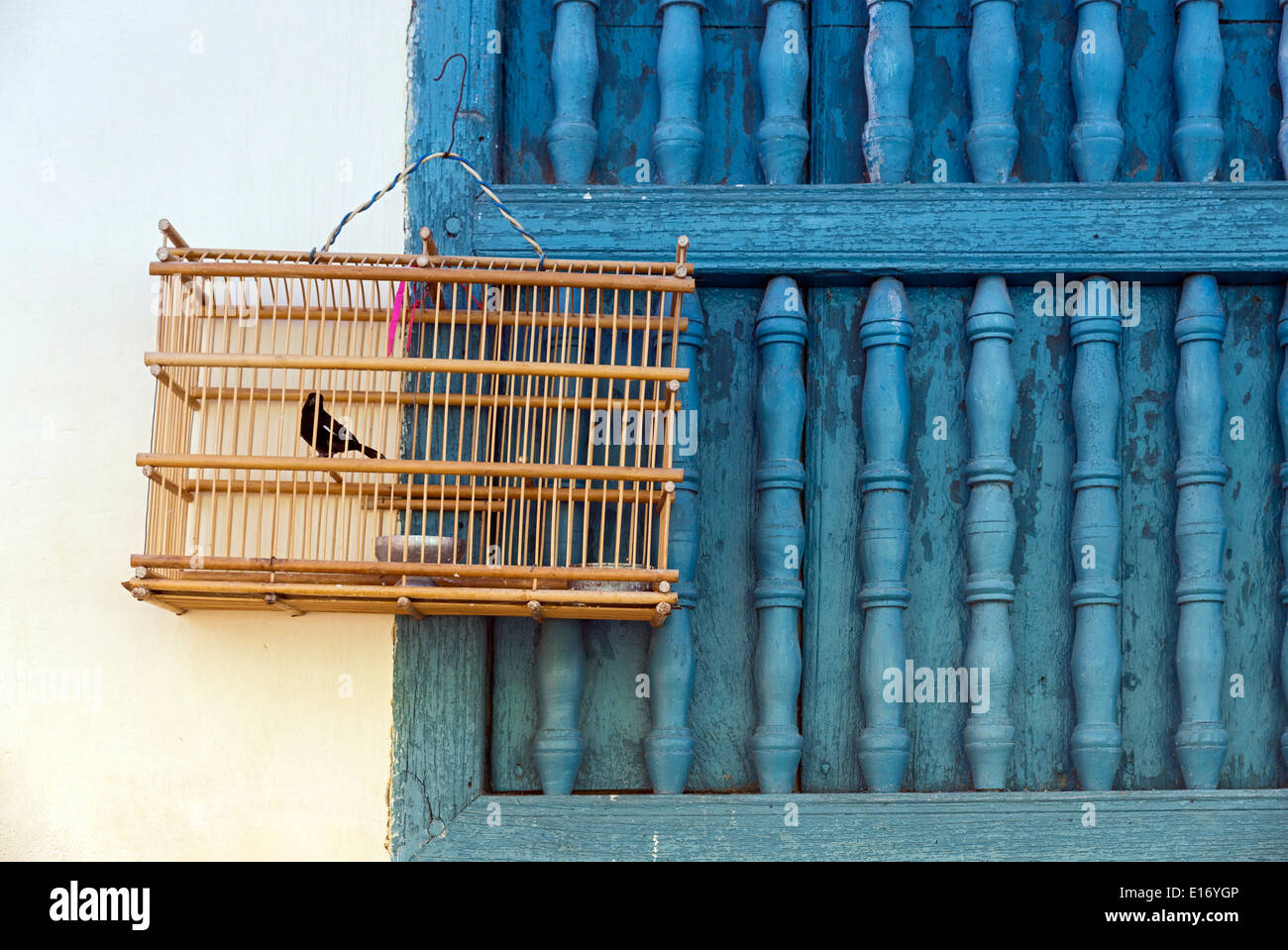 bird cage on a wall with blue window. Trinidad, Cuba Stock Photo