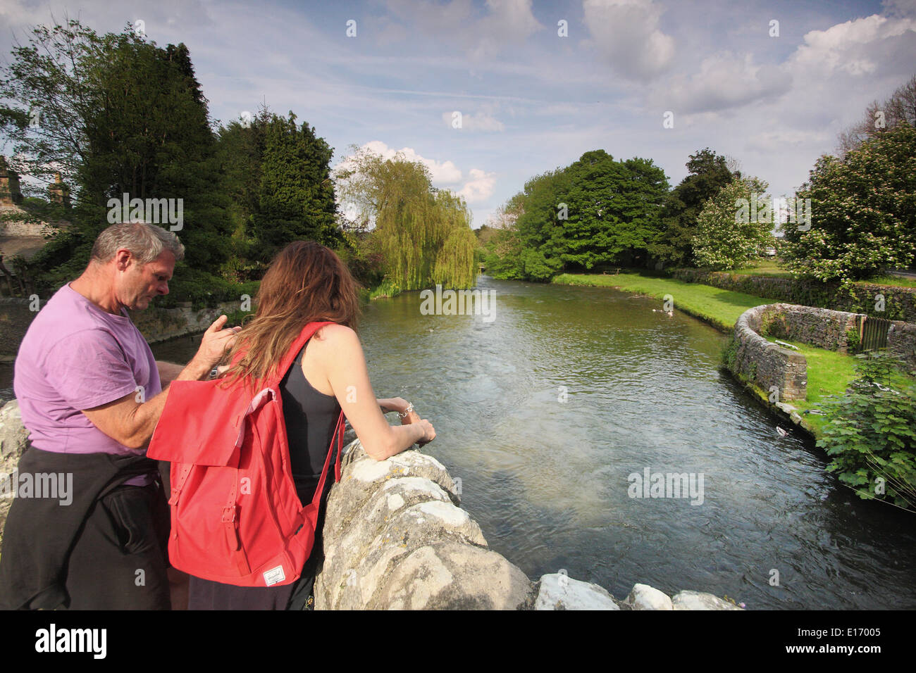 Walkers pause to study a map on the medieval bridge over the River Wye at Ashford-in-the-Water, Peak District, England, UK - May Stock Photo