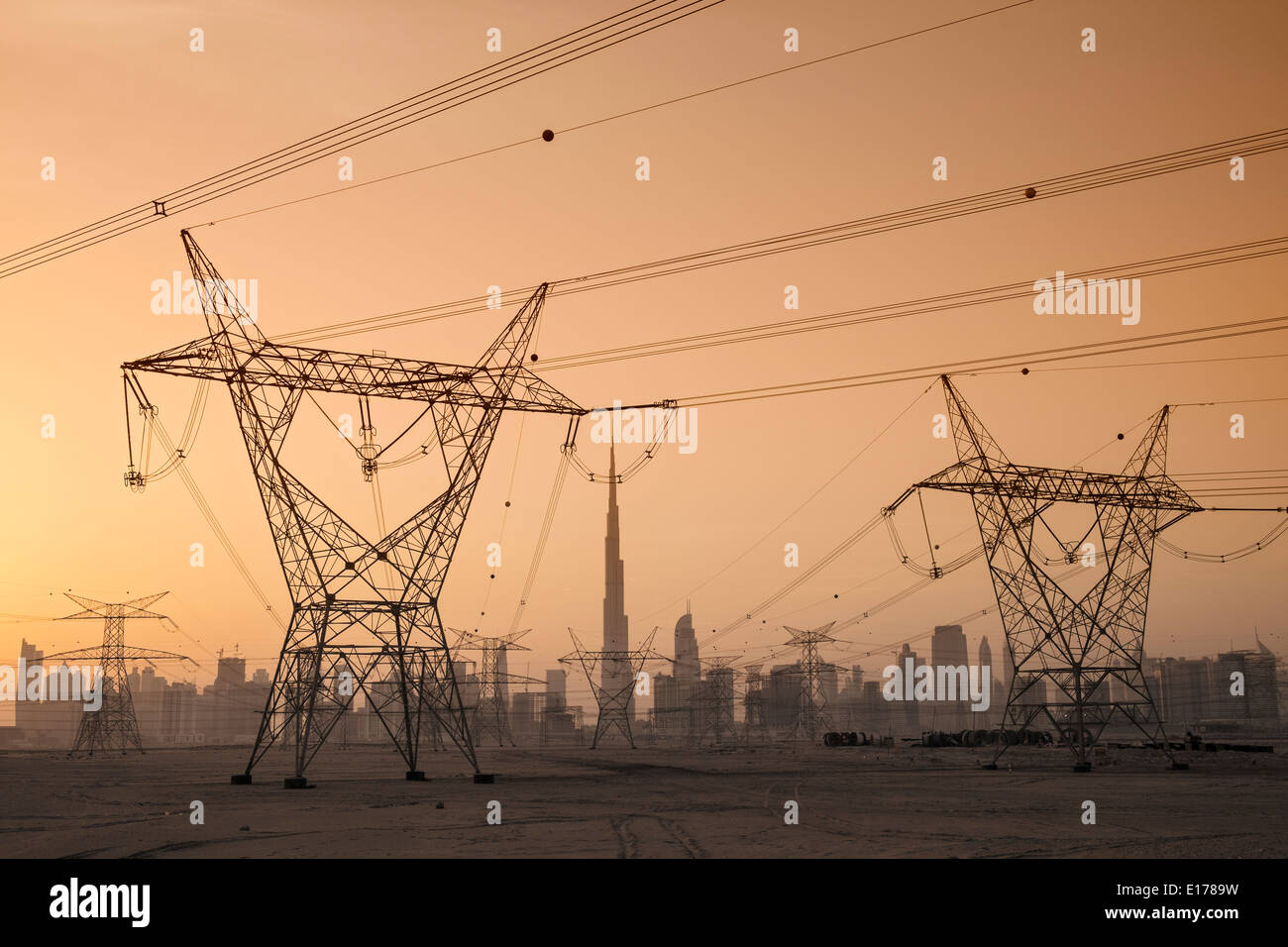 Electricity transmission lines and pylons and skyline at dusk in Dubai United Arab Emirates Stock Photo