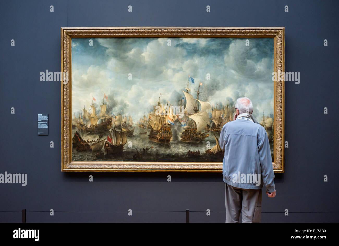 Man looking at The Battle of Terheide by Jan Abrahamsz Beerstraten in the Rijksmuseum, Amsterdam, the Netherlands. Stock Photo