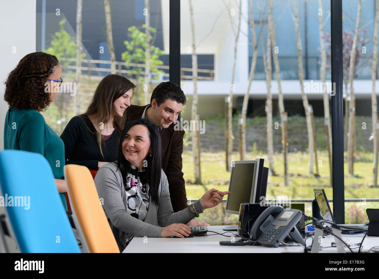 Office workers discussing a project while looking at a computer screen Stock Photo