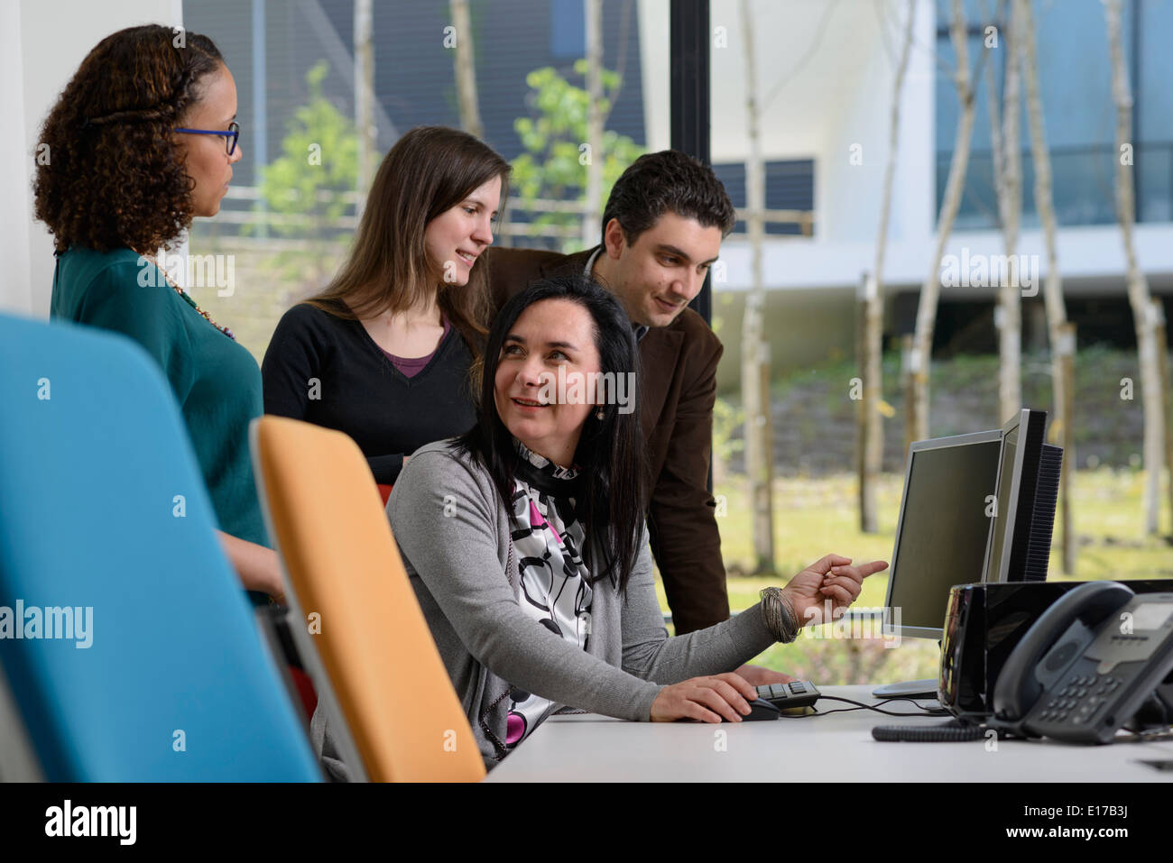 Office workers discussing a project while looking at a computer screen Stock Photo