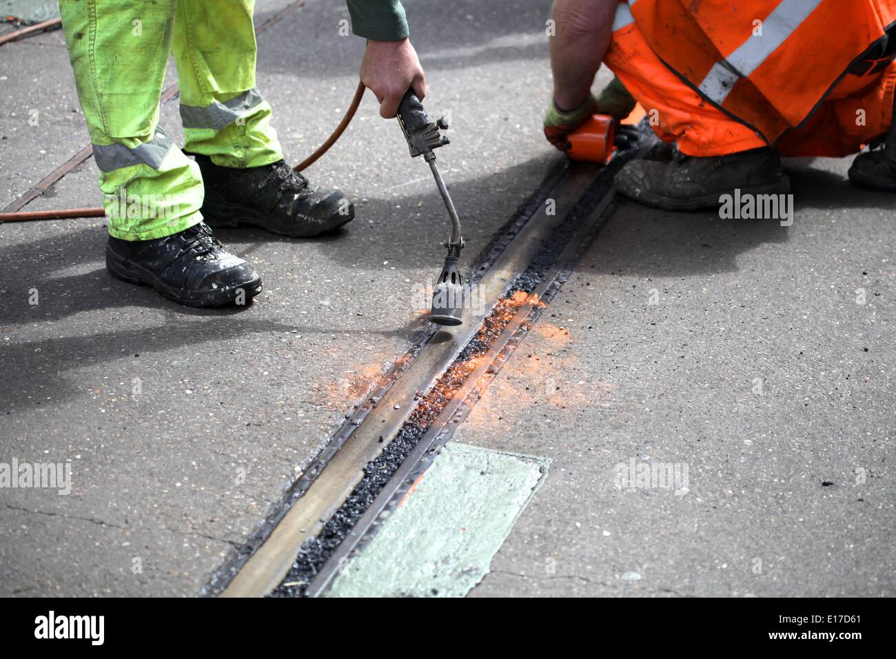 Nottingham, UK. 25th May 2014. Milk Race. Workers fill in the tram tracks to stop cyclists' tyres getting stuck in them Credit:  Neville Styles/Alamy Live News Stock Photo
