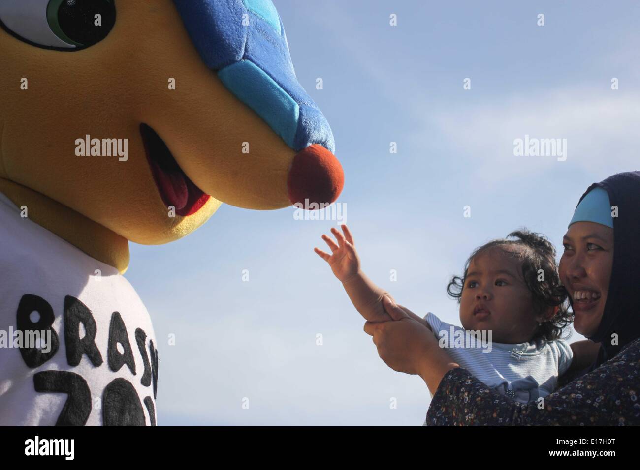 Semarang, Central Java, Indonesia. 25th May, 2014. SEMARANG, CENTRAL JAVA, INDONESIA - MAY 25: A girl touch Armadillo, the 2014 World Cup mascot, to welcome the 2014 FIFA World Cup, International men's football tournament scheduled to take place in Brazil from 12 June to 13 July 2014, in Semarang, Central Java, Indonesia on May 25, 2014. Credit:  Sijori Images/ZUMAPRESS.com/Alamy Live News Stock Photo