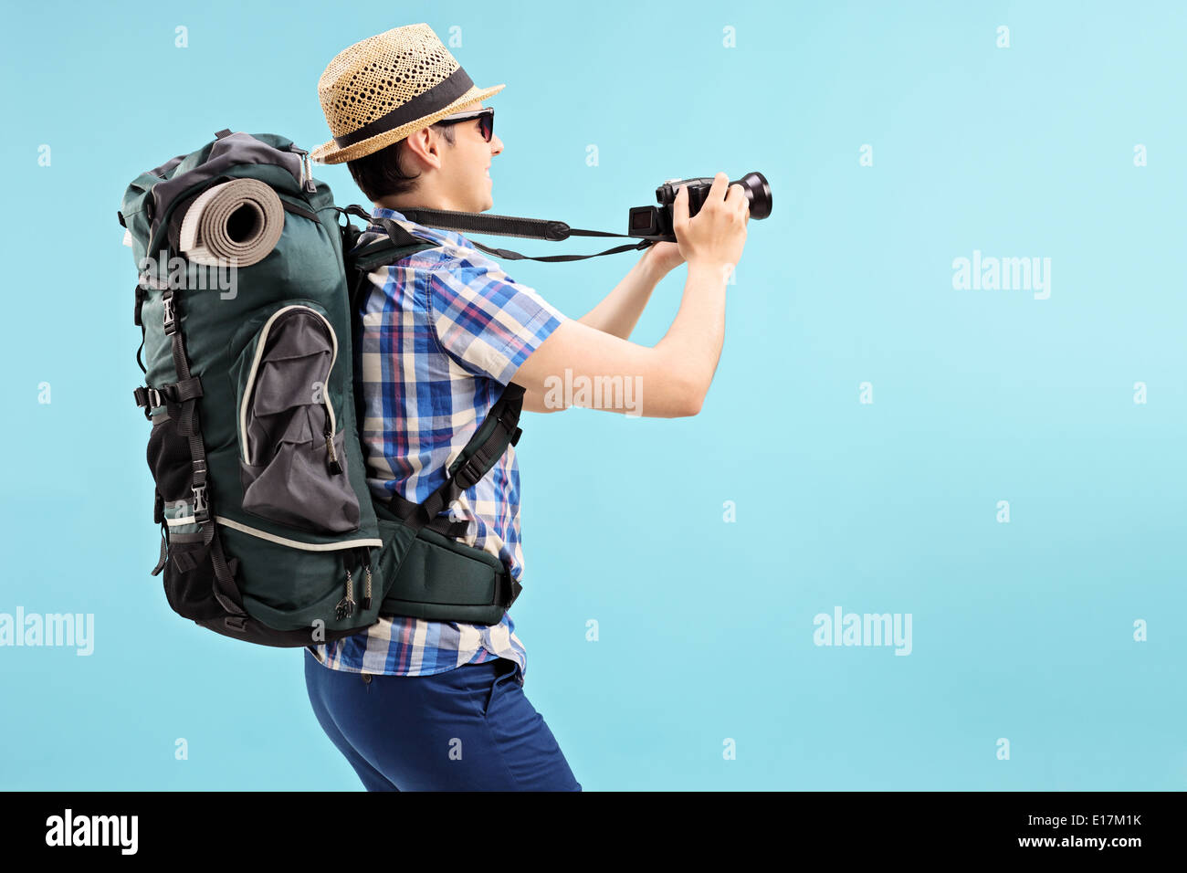 Young tourist taking a picture with camera on blue background Stock Photo
