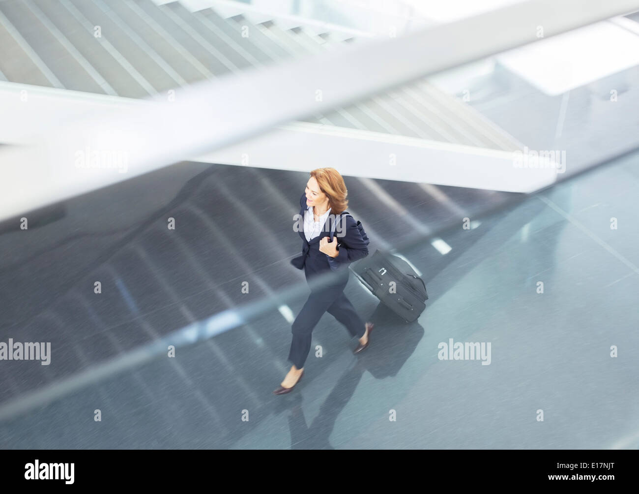 Businesswoman pulling suitcase in lobby Stock Photo