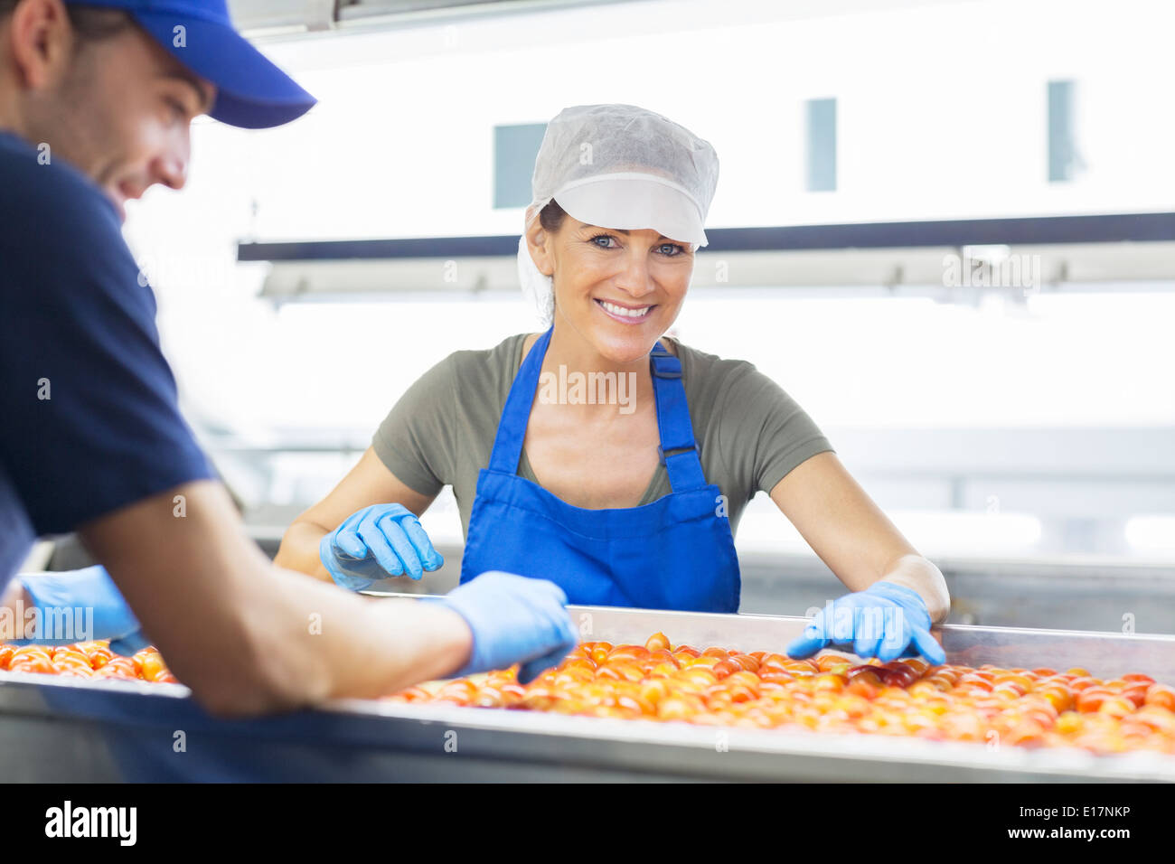 Portrait of confident worker examining tomatoes in food processing plant Stock Photo
