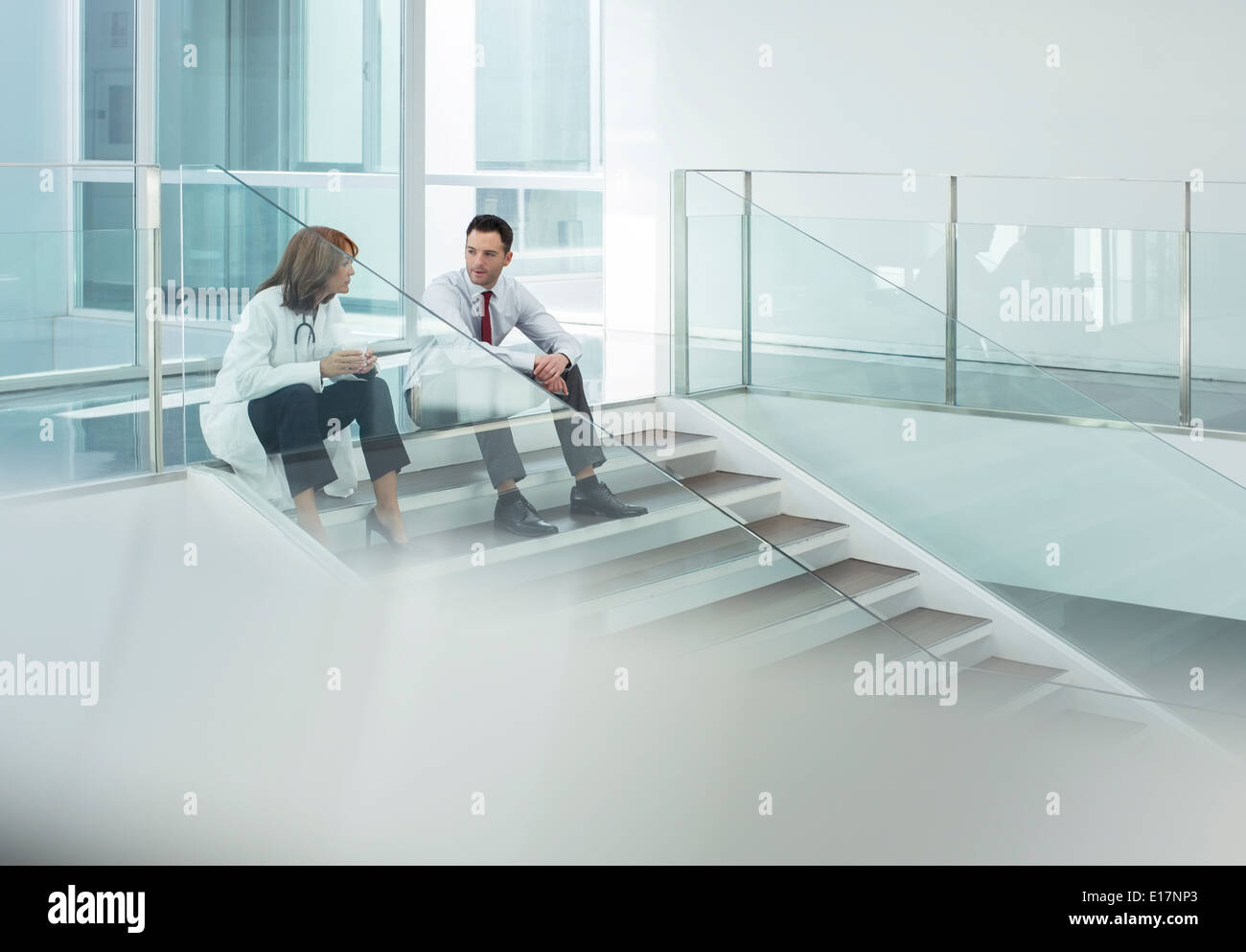 Doctor and administrator talking on hospital stairs Stock Photo