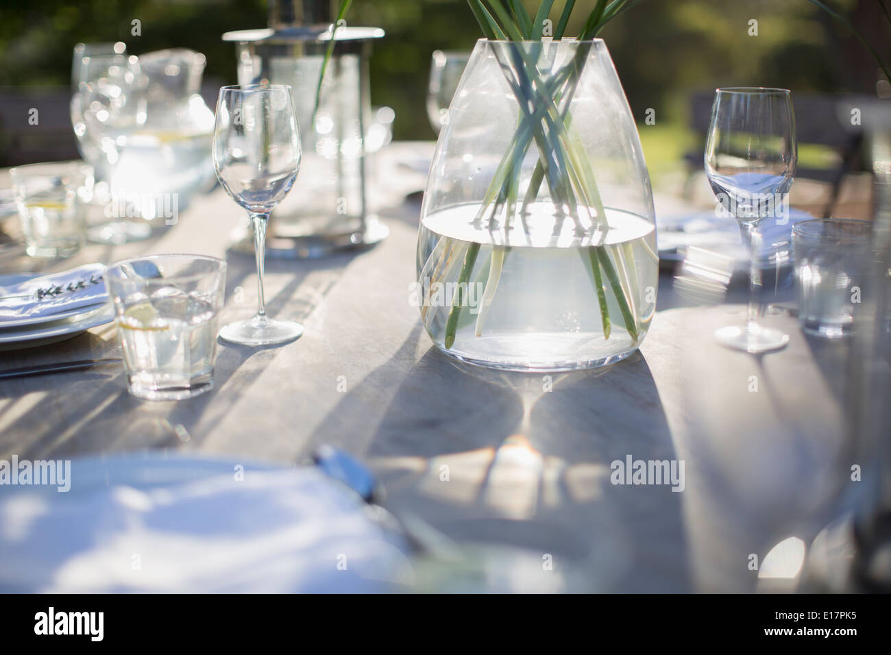 Vase and place settings on sunny patio table Stock Photo