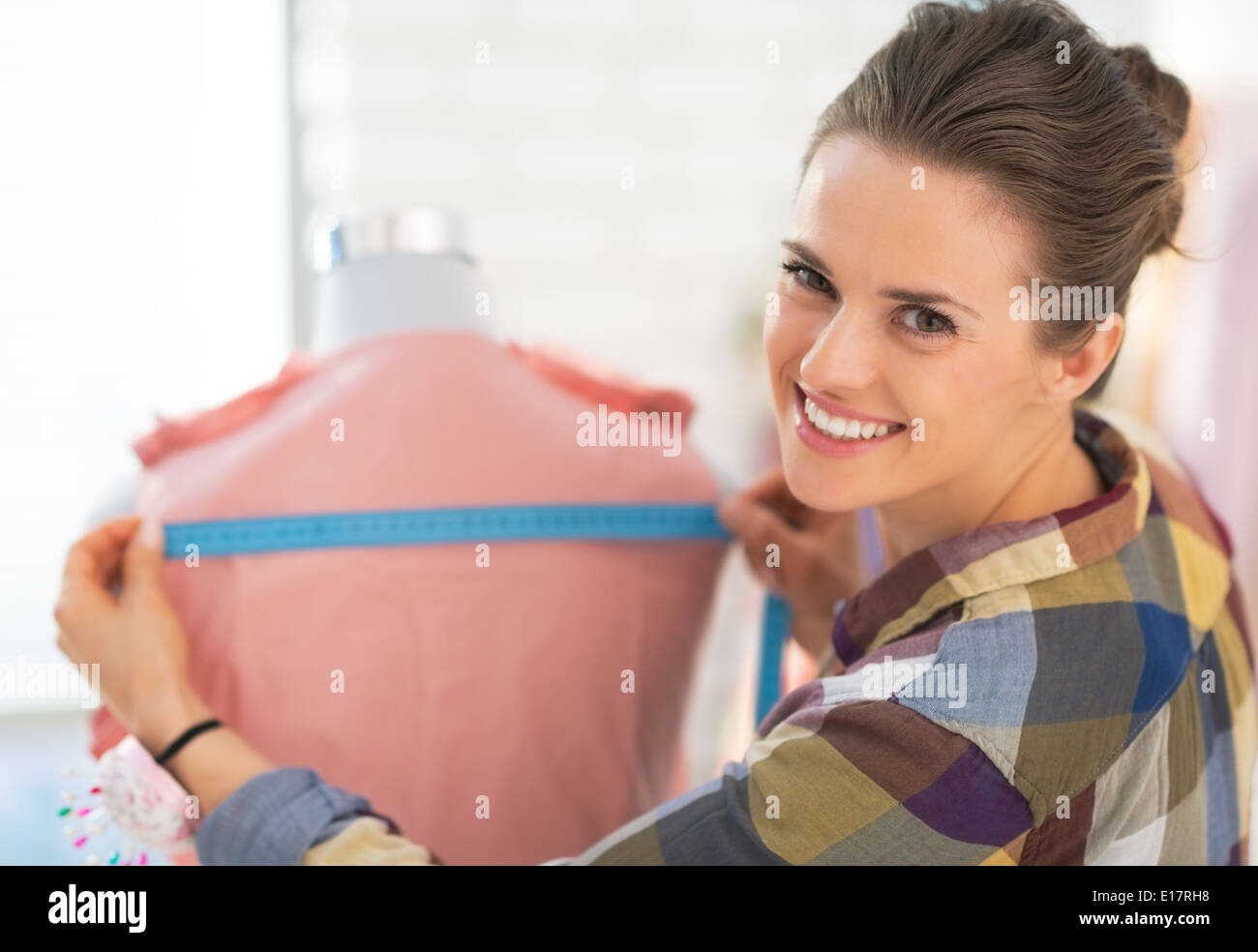 Happy seamstress measuring garment on mannequin Stock Photo Alamy