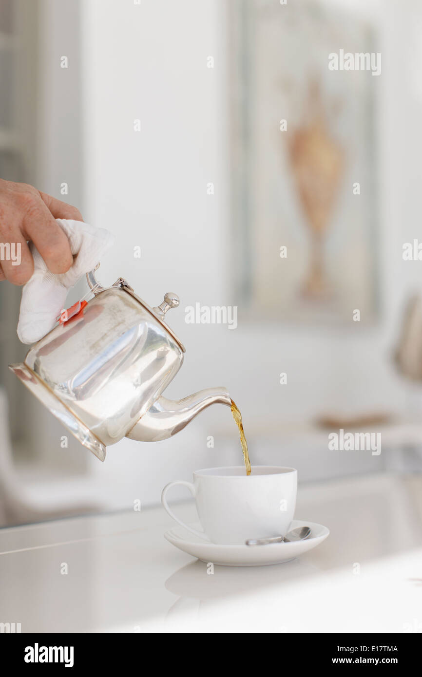 Hand pouring tea from silver teapot hires stock photography and images