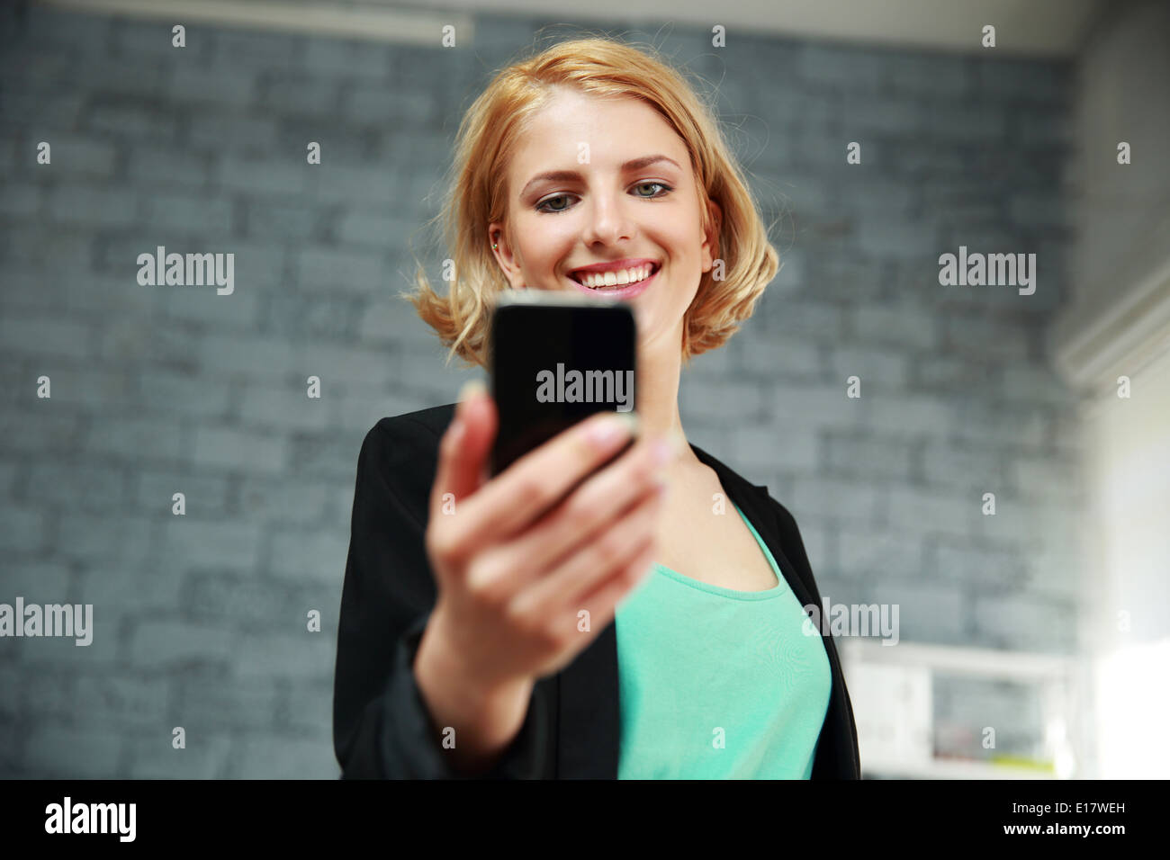 Young smiling woman holding smartphone in office Stock Photo - Alamy