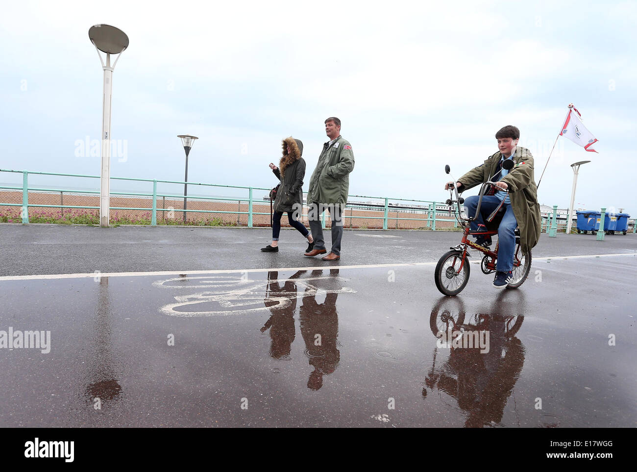 A young boy on a Raleigh Chopper bike, cycles along Brighton seafront on a rainy Bank Holiday. Stock Photo
