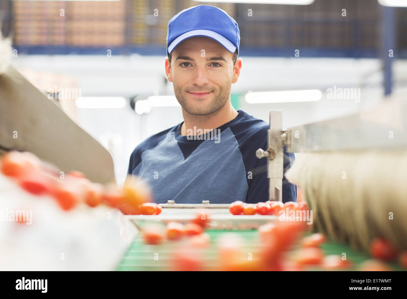 Portrait of worker at conveyor belt in food processing plant Stock Photo