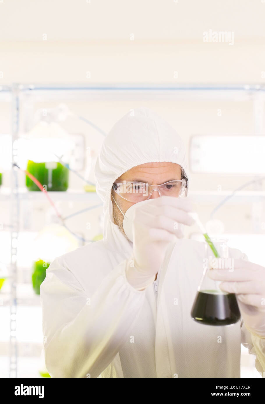 Scientist in clean suit with beaker in laboratory Stock Photo