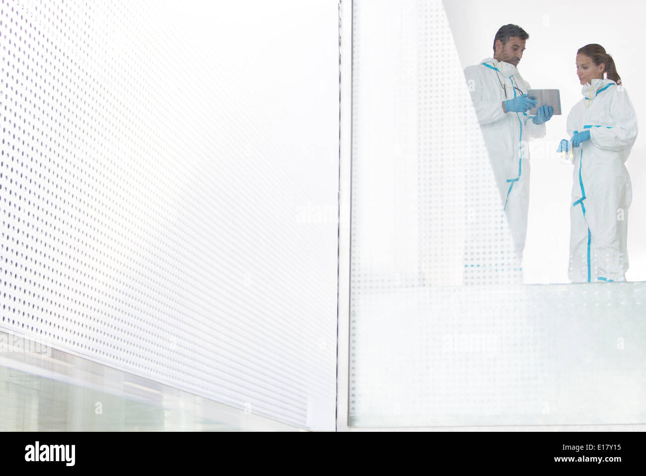 Scientists in clean suits using digital tablet Stock Photo