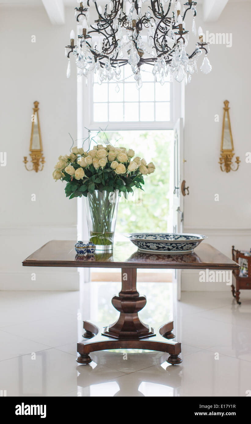 Chandelier over bouquet on table in luxury foyer Stock Photo