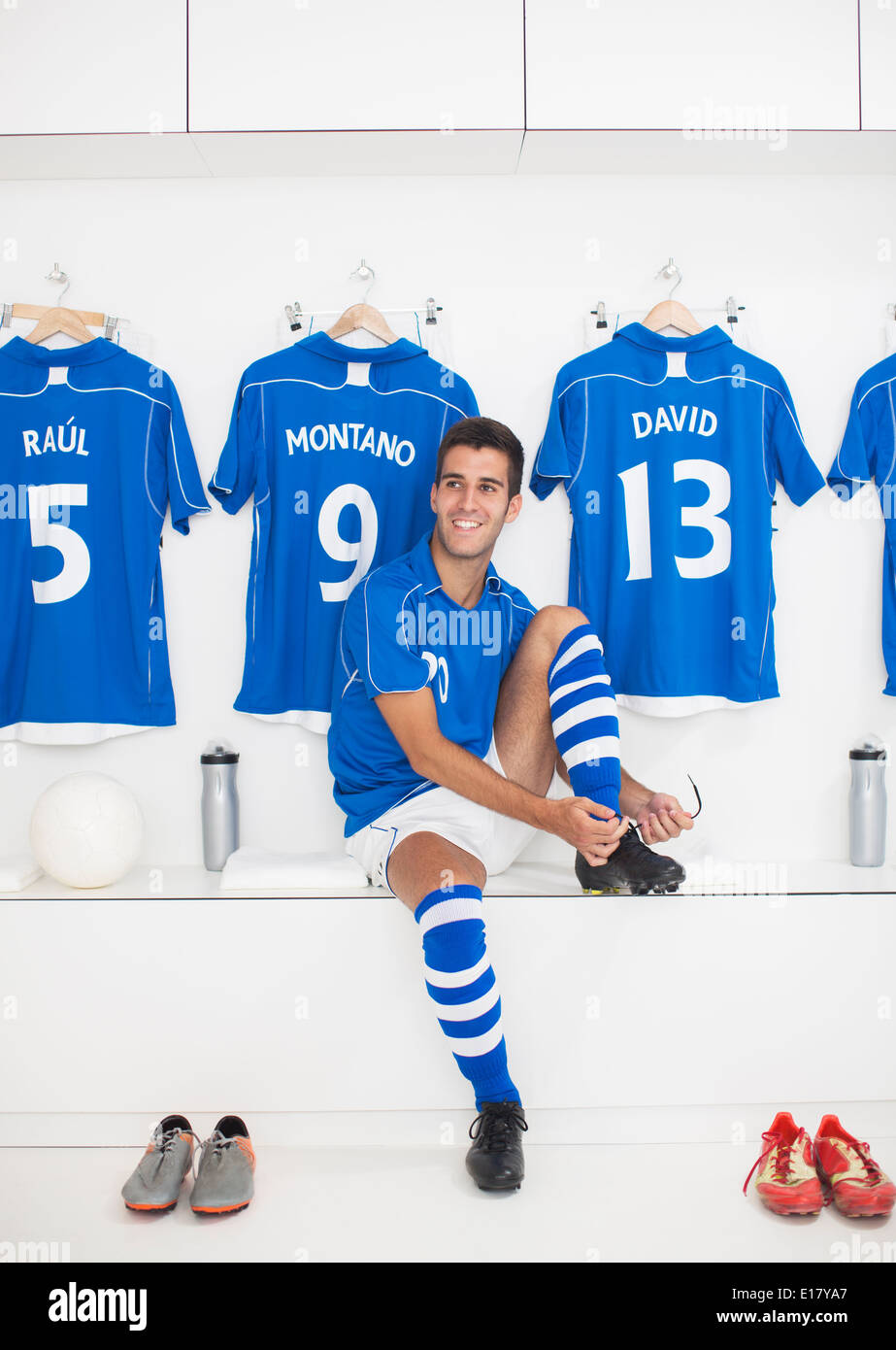 Soccer player putting on shoes in locker room Stock Photo