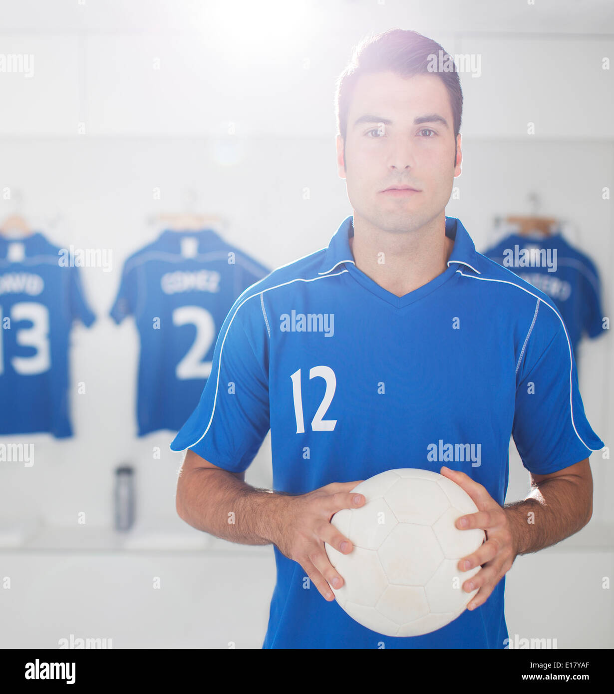 Soccer player holding ball in locker room Stock Photo