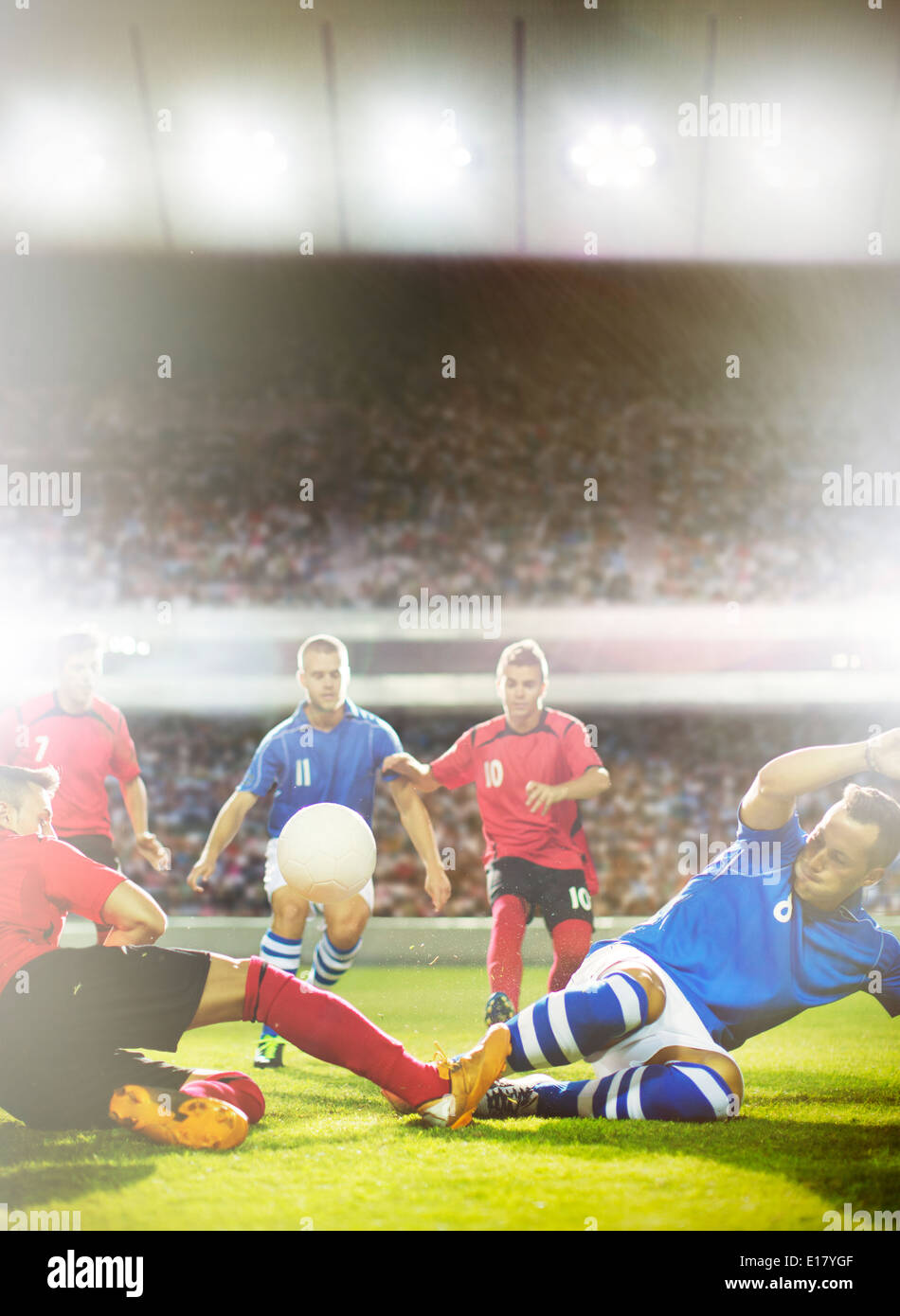 Soccer players kicking at ball on field Stock Photo