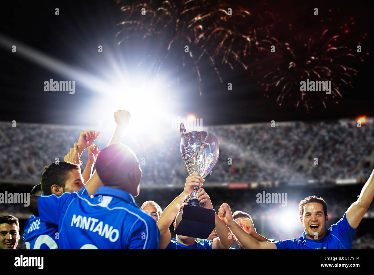 Soccer team celebrating with trophy on field Stock Photo