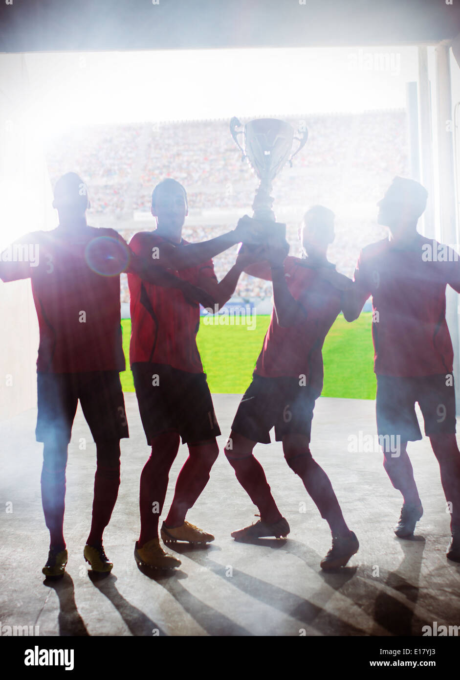 Silhouette of soccer players holding trophy Stock Photo