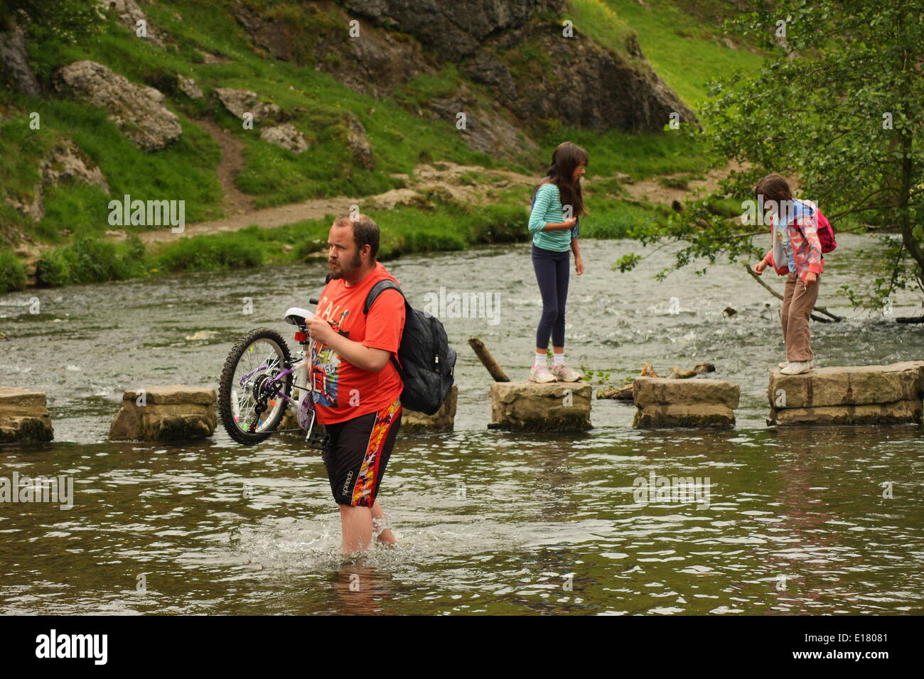 A family crosses the stepping stones of the River Dove at Dovedale in the Manifold Valley,Peak District, Derbyshire, England, UK Stock Photo