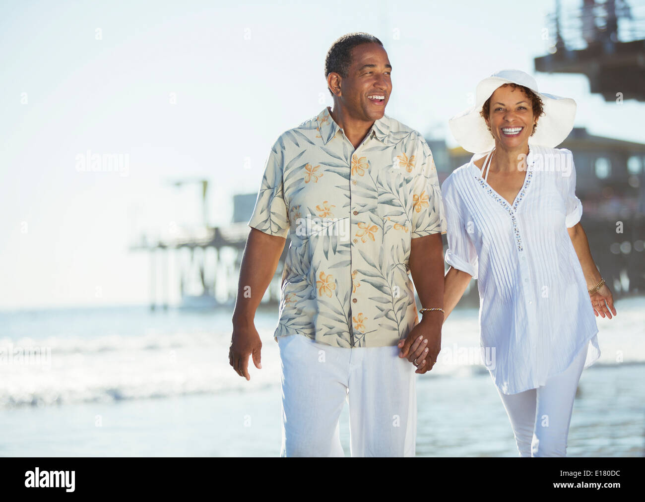 Couple holding hands and walking on beach Stock Photo