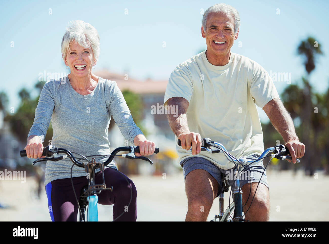 Portrait of senior couple riding bicycles on beach Stock Photo