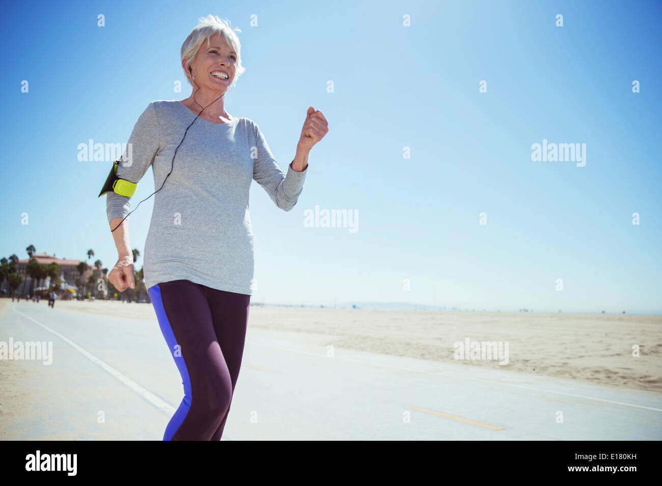 Senior woman jogging on beach boardwalk Stock Photo
