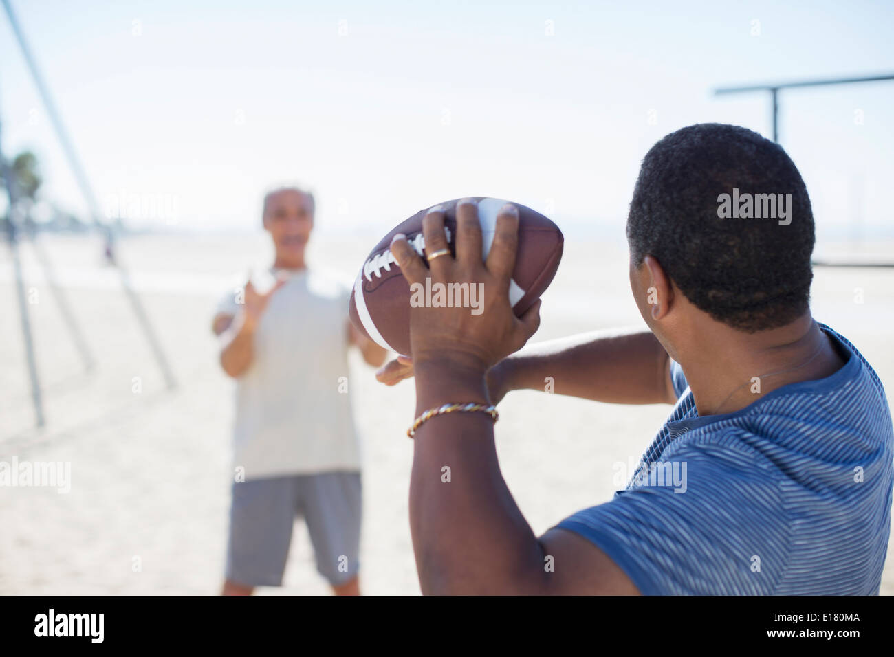 Senior men playing football on beach Stock Photo