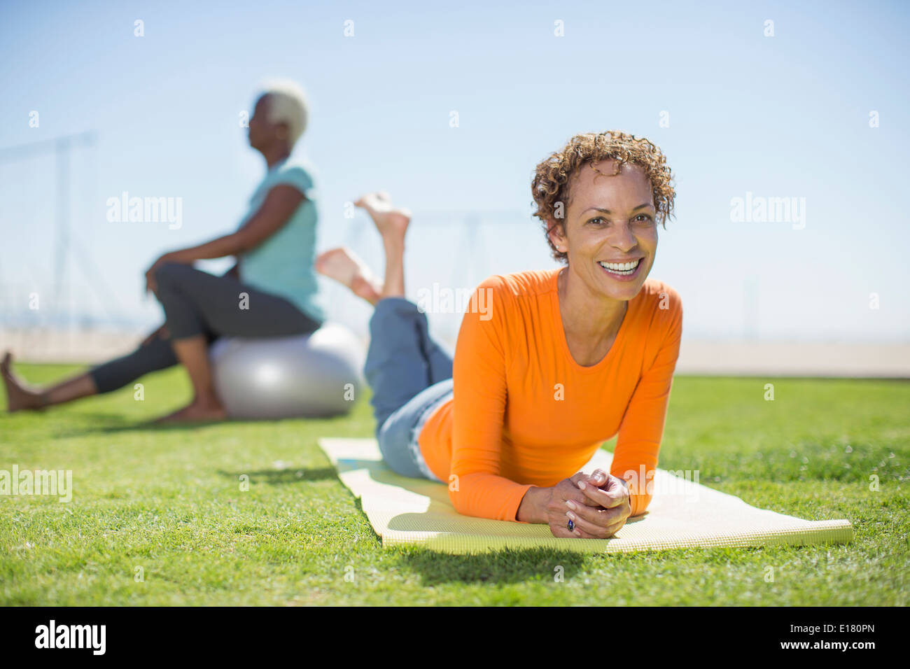Portrait of smiling woman on yoga mat in park Stock Photo
