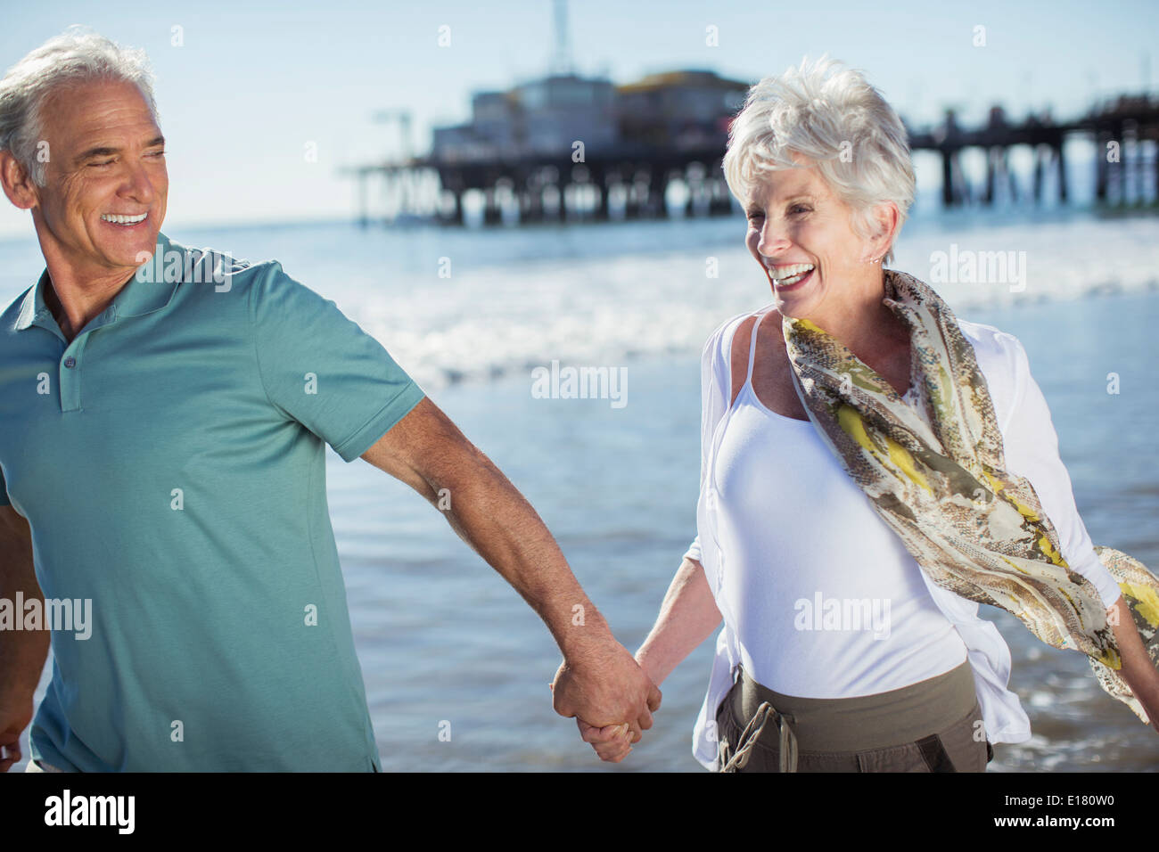 Enthusiastic senior couple running on beach Stock Photo