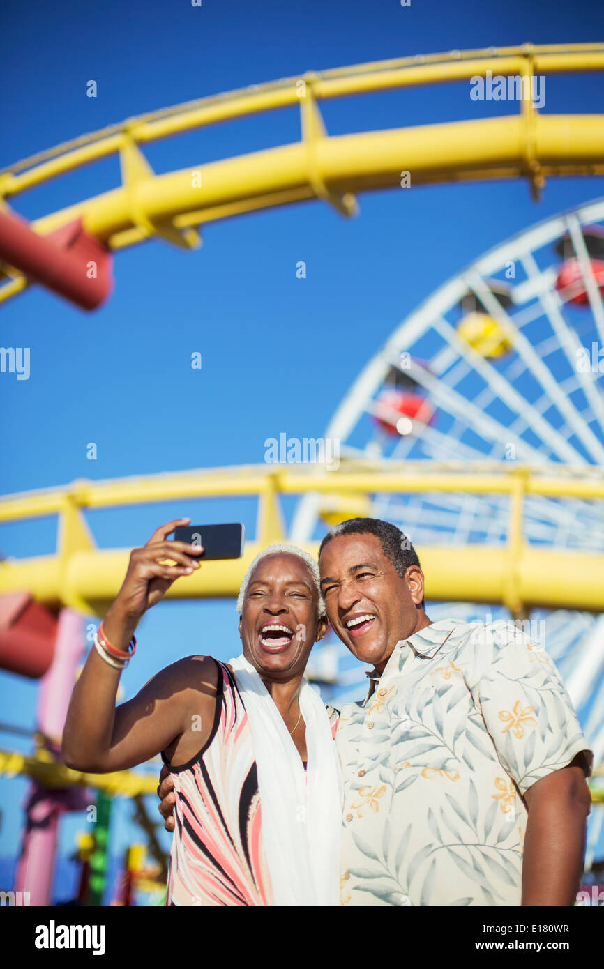 Senior couple taking selfie at amusement park Stock Photo
