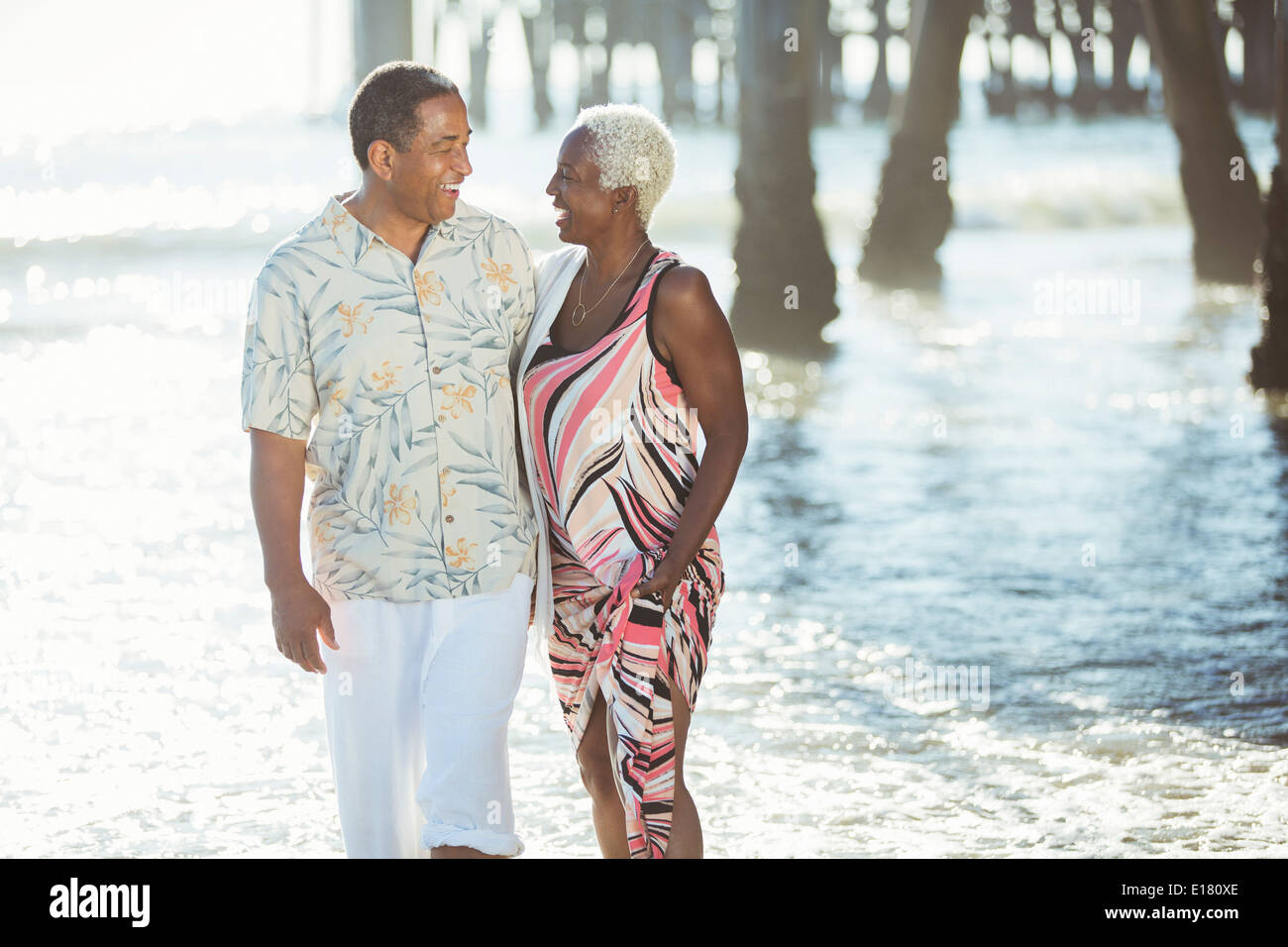Senior couple walking on sunny beach Stock Photo