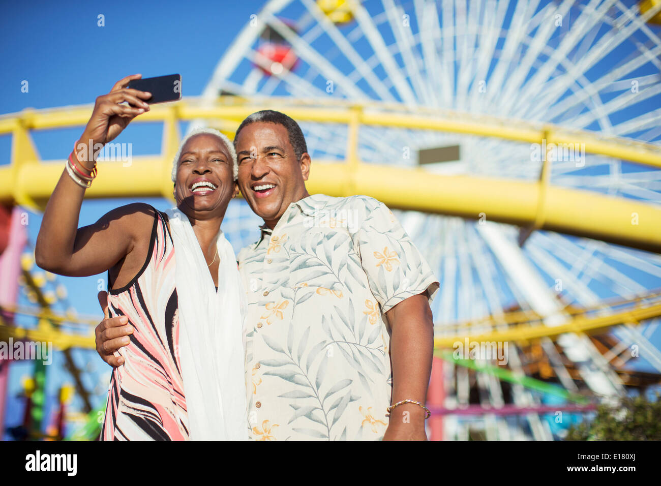 Senior couple taking selfie at amusement park Stock Photo