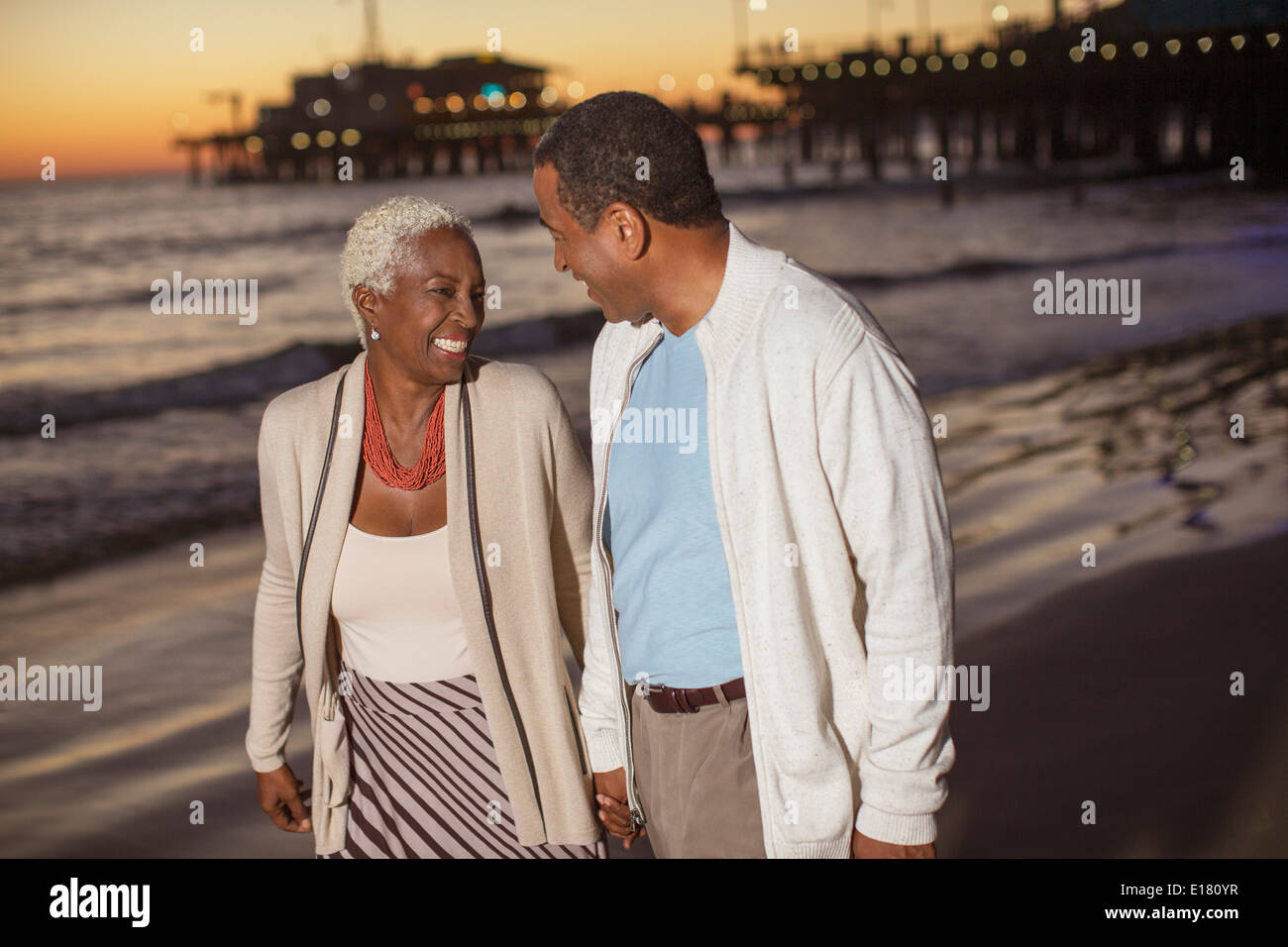 Senior couple walking on beach at sunset Stock Photo