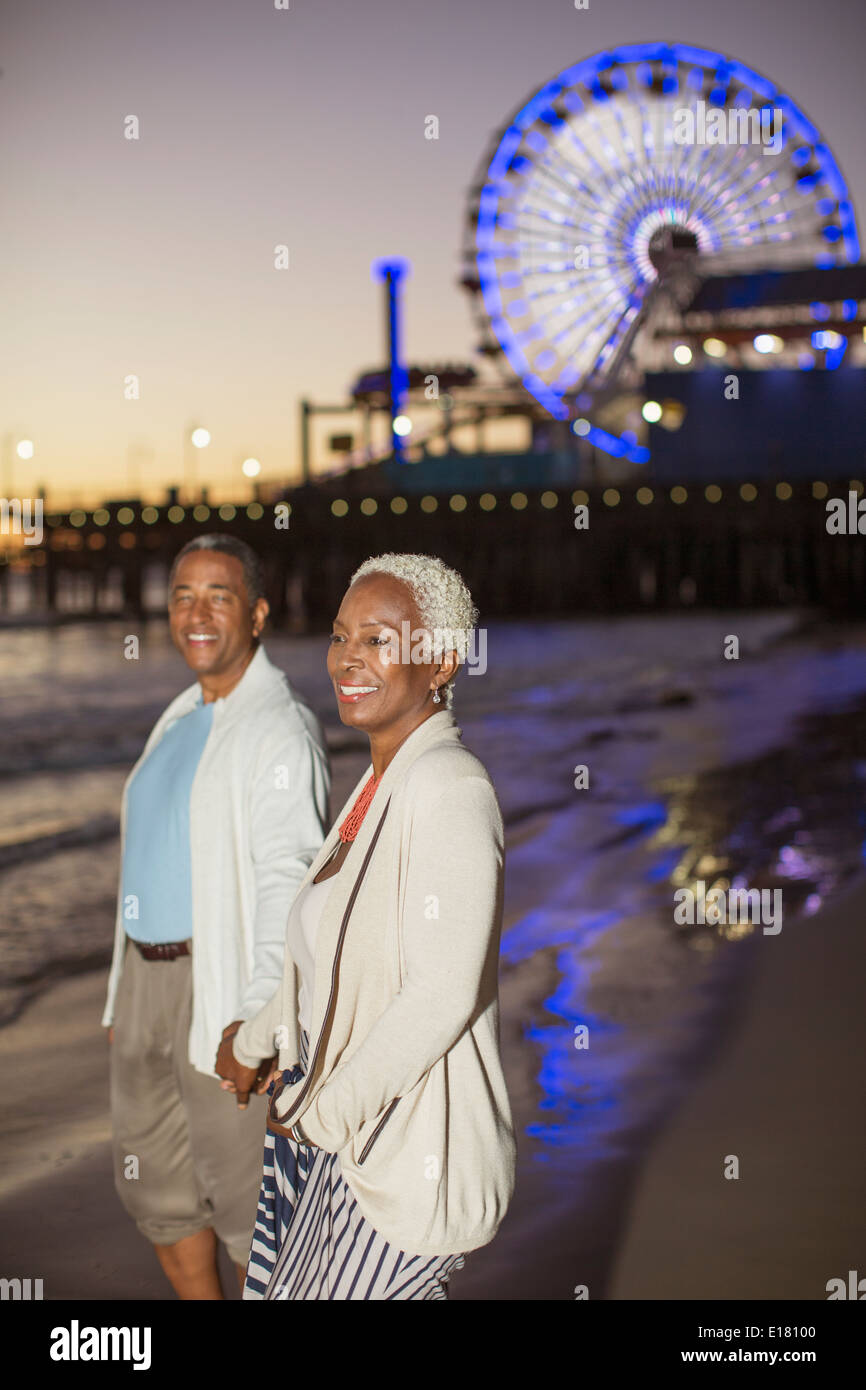 Senior couple walking on beach at sunset Stock Photo