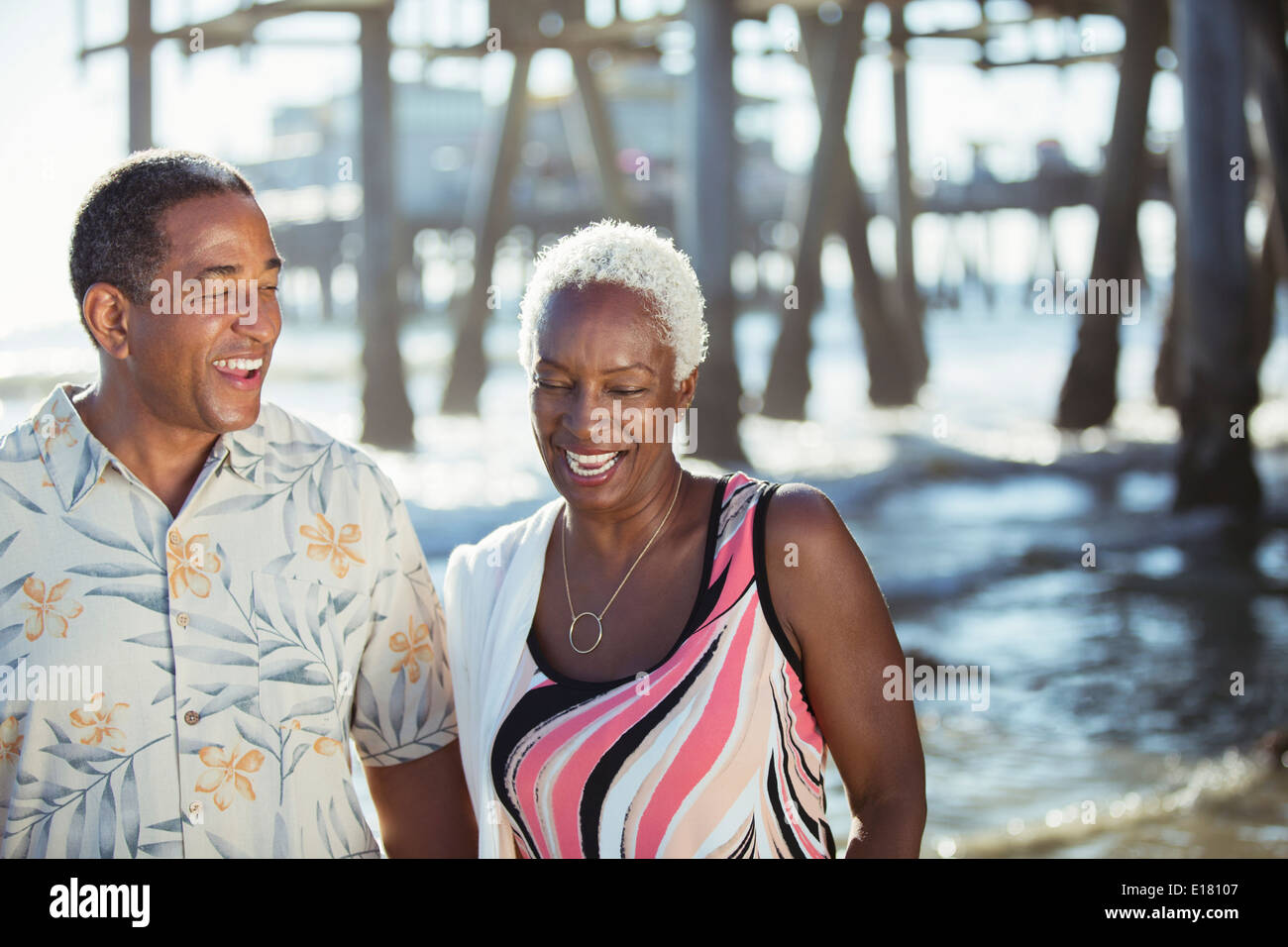 Senior couple on beach near pier Stock Photo