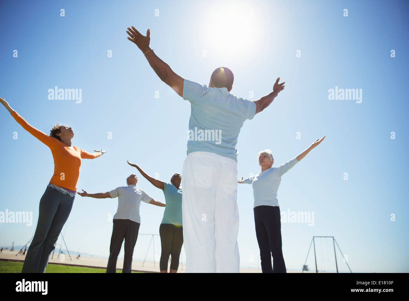 Seniors practicing yoga under sunny blue sky Stock Photo