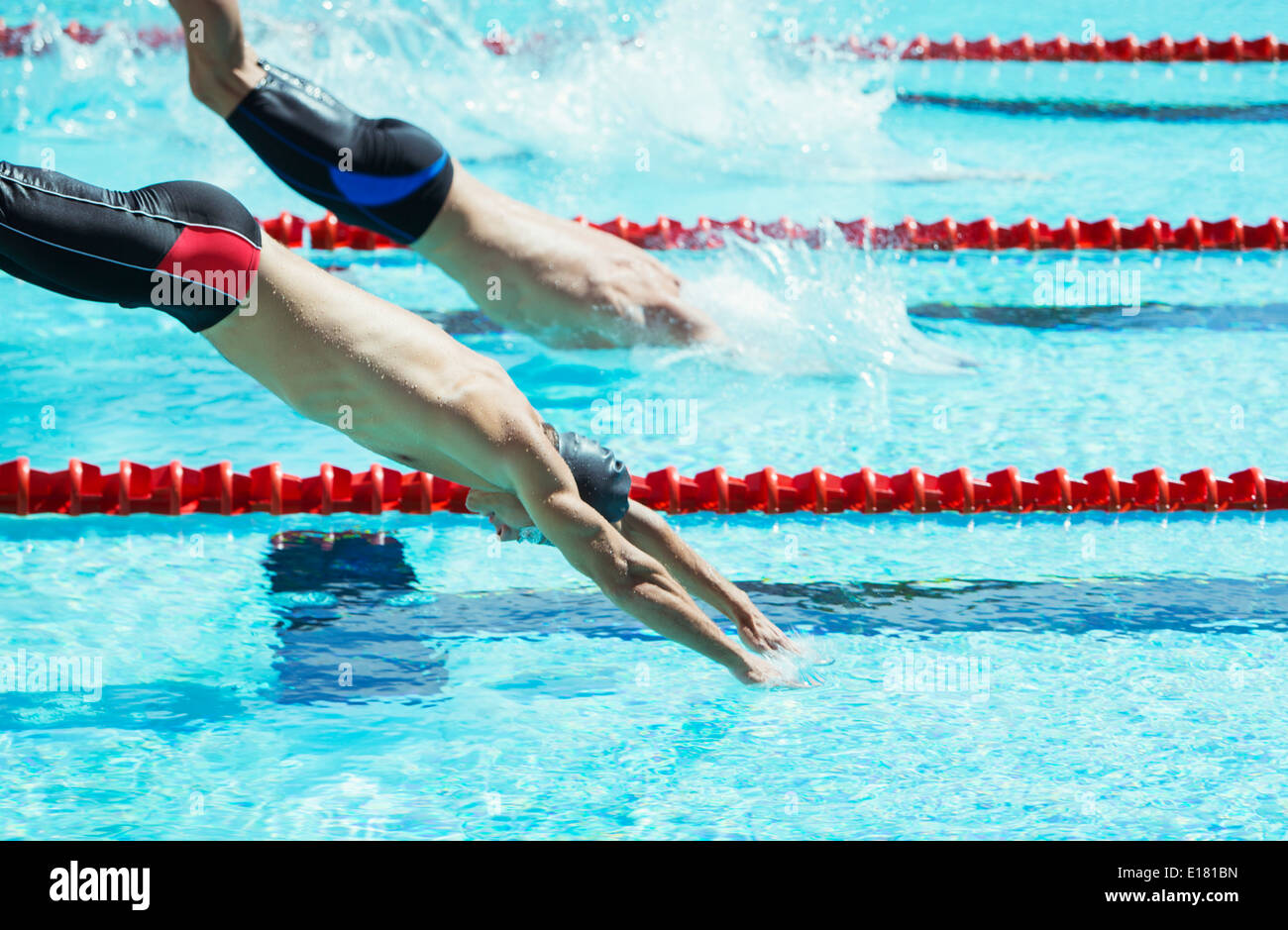 Swimmers diving into pool Stock Photo